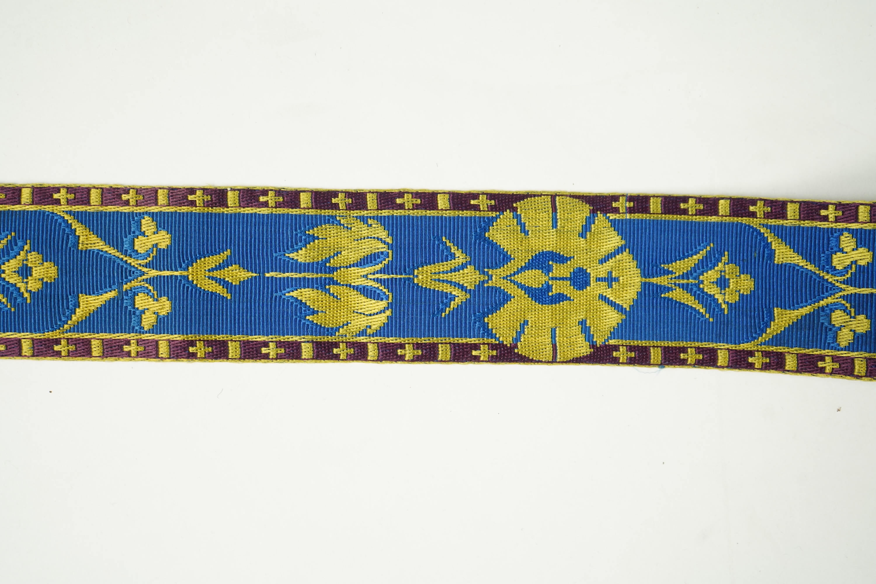 Three long lengths of late 19th century silk woven braiding. One woven in gold, turquoise and maroon silk, possibly for ecclesiastic use, in Christopher Dresser ‘style’ motifs, another in gold and black silk thread in a